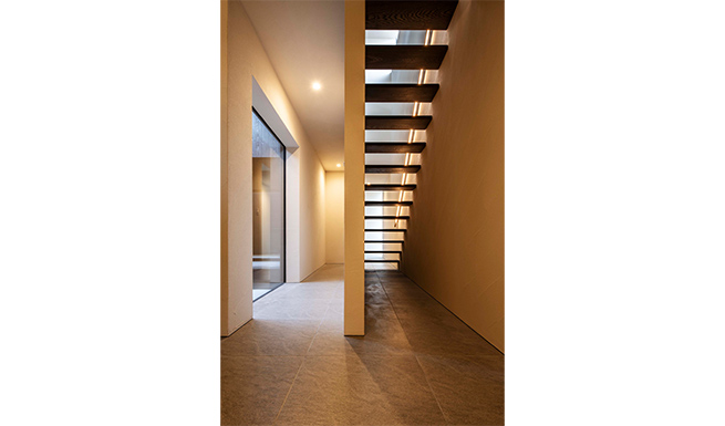 エントランスより階段ホールを望む。左側のメインCOURTと吹抜上のハイサイドライトからの光で満たされる。