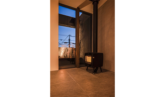 薪ストーブのあるリビングよりテラスのライトアップされた植栽を望む。