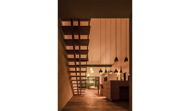 エントランスからの階段、リビング夕景。ライトアップされた南側庭とテラス越しに一体となる。